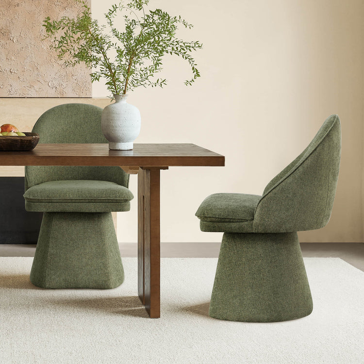 Two green swivel chairs placed by a wooden dining table, with a decorative vase and plant in the background.