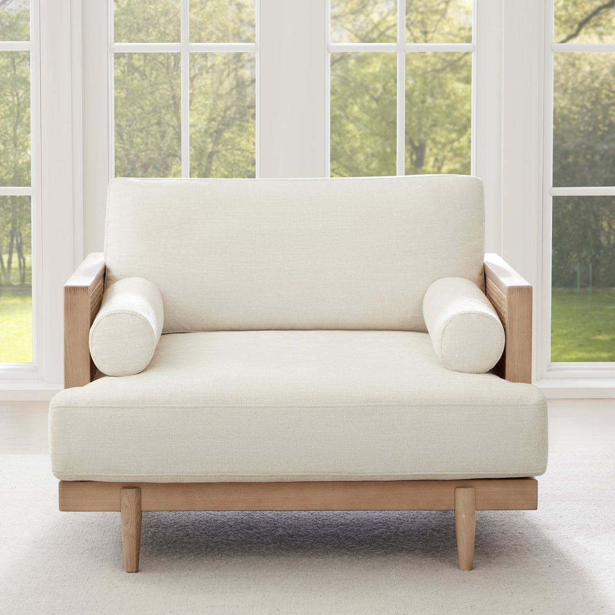 Julane cane armchair with light fabric and natural wood frame in a bright interior - CHITA Living
