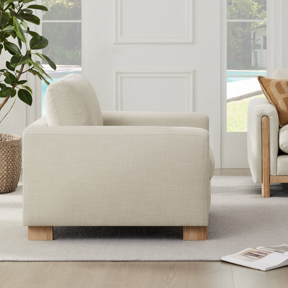 Side view of light gray Keaton Armchair showcasing its plush cushions and wooden legs - CHITA Living